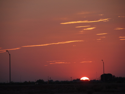 [Only the top third of the white-yellow orb is now visible above the horizon. The color of the sky has changed to a purplish-red.]